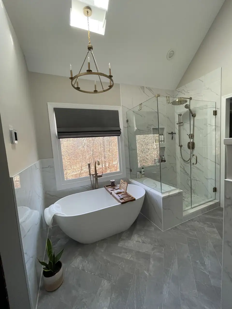 Bright bathroom with a freestanding soaking tub, frameless glass shower and white marble-look tile, bathroom remodeling Raleigh-Durham NC