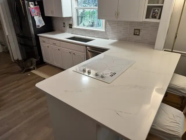 L-shaped white kitchen countertop with a built-in cooktop and undermount sink